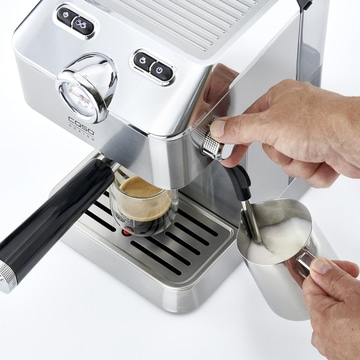 Espresso machine with milk frother. Stainless steel design. Coffee being made.