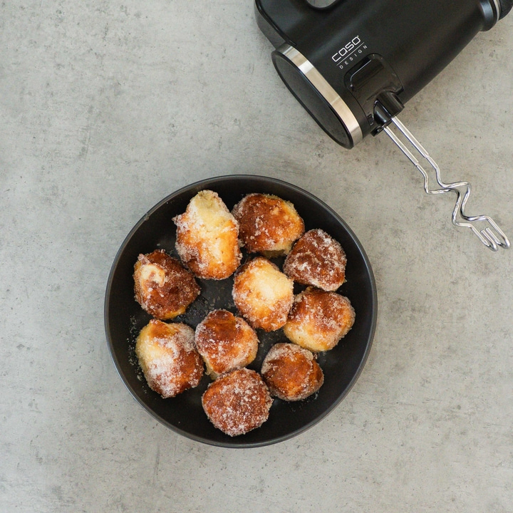 Plate of donuts, hand mixer on gray surface, close-up shot
