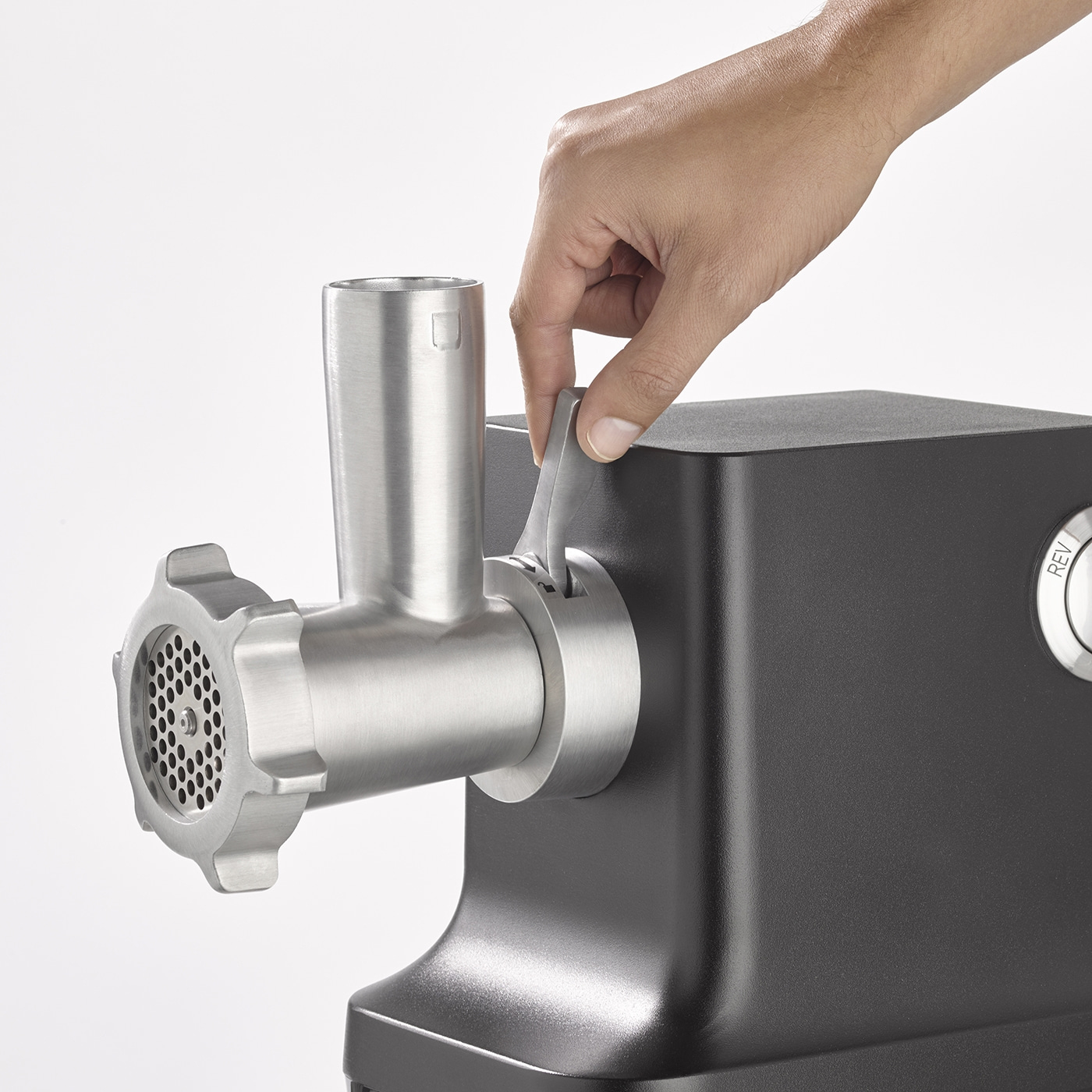 Nahaufnahme einer Person, die einen Fleischwolf bedient, mit hellem Hintergrund.