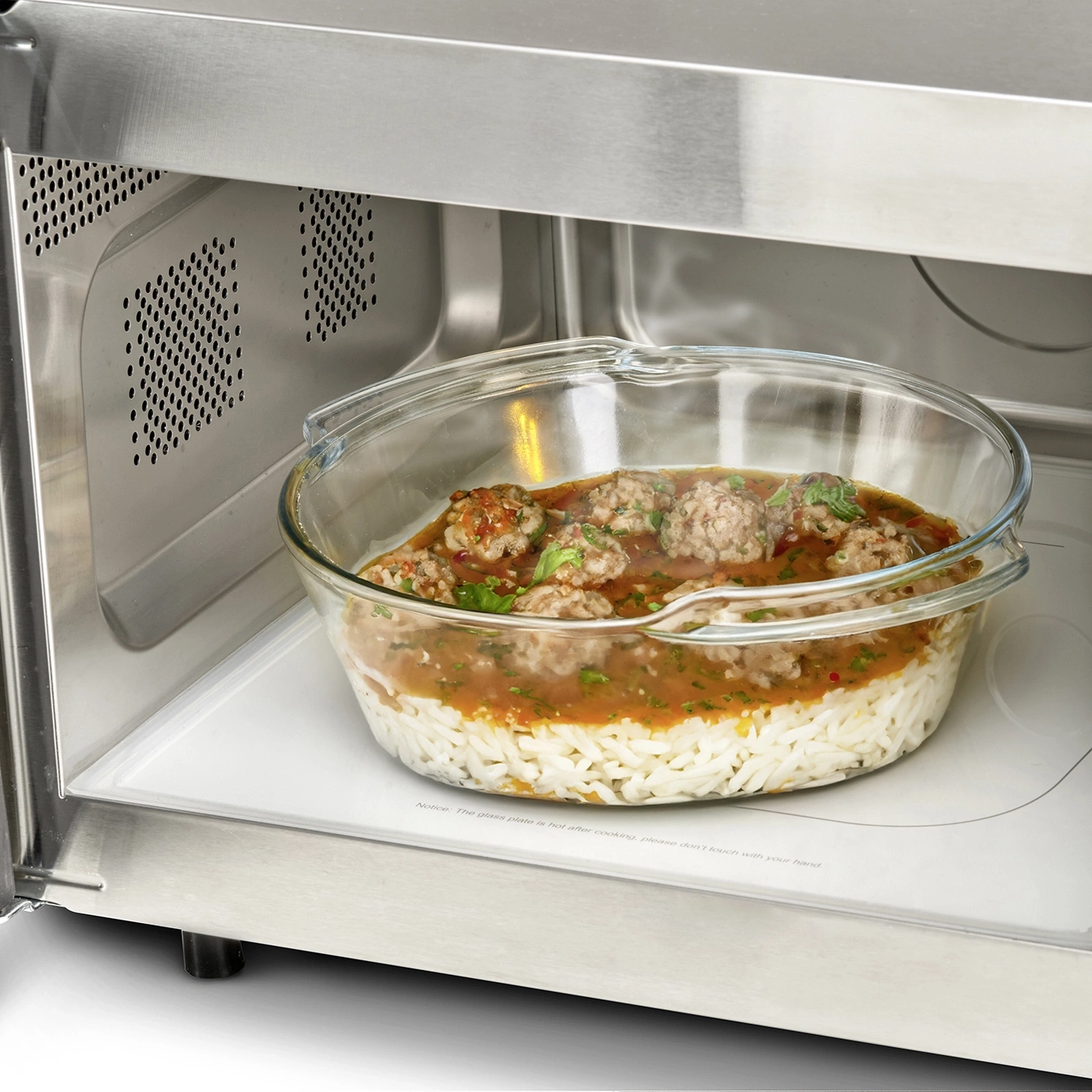 Microwave with rice, meatballs, and sauce in a glass dish. Warning: hot!