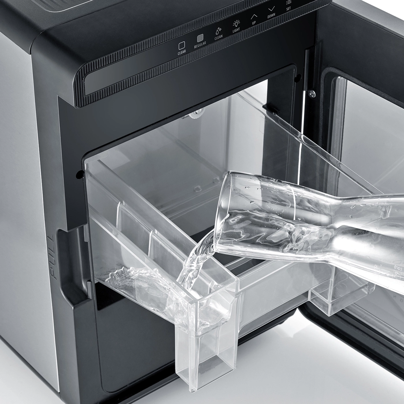 Water is poured into an ice maker inside a cabinet.