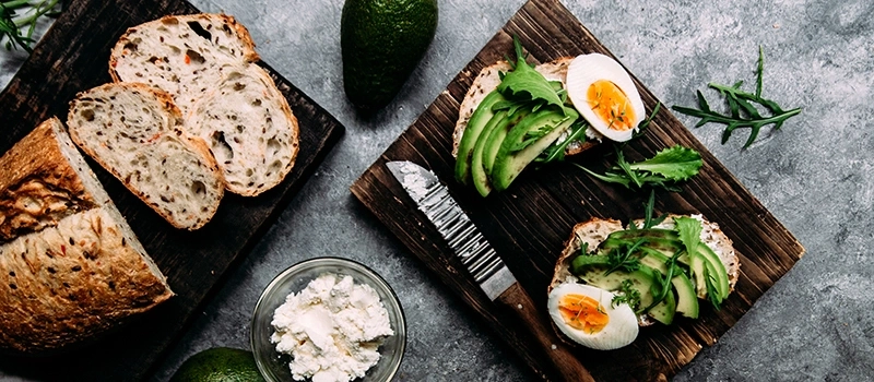 Avocado toast with eggs and bread on wooden board, close-up shot