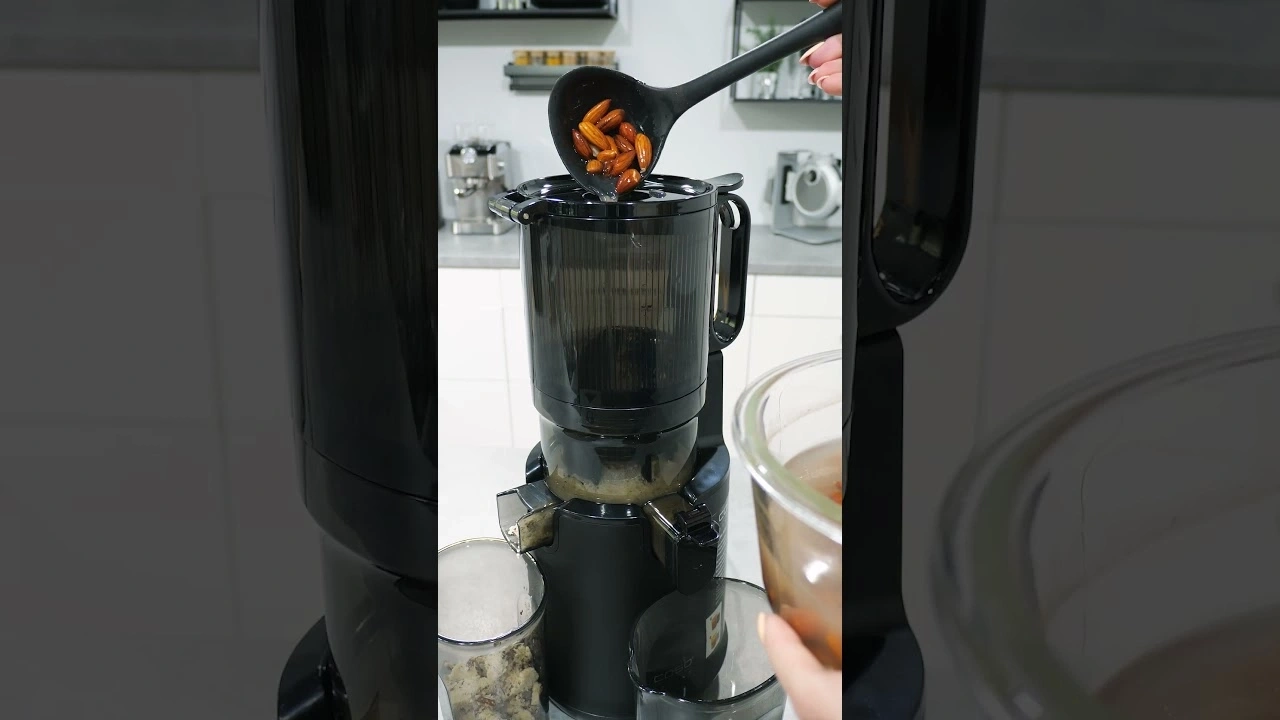 Person pouring ingredients into a juicer. Kitchen, appliance, food preparation.