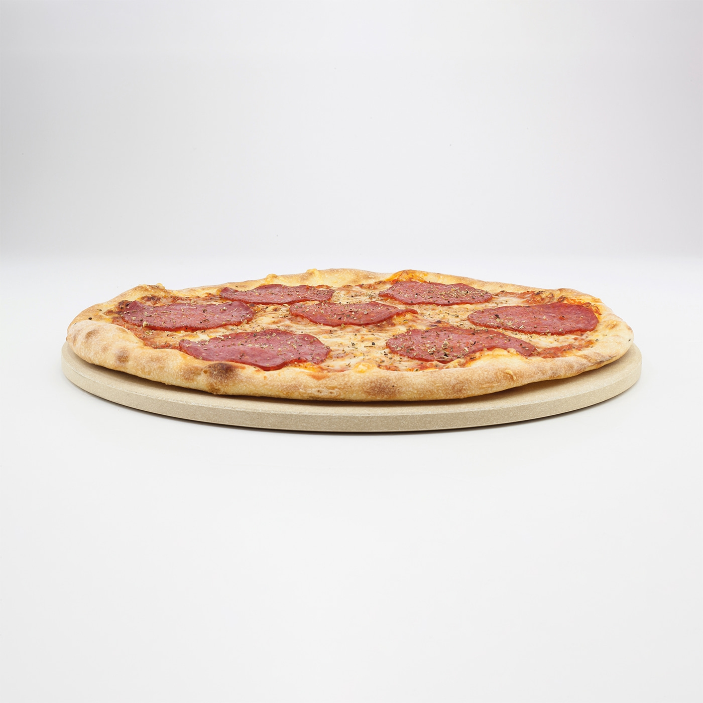 Pizza with salami on a pizza stone against a white background