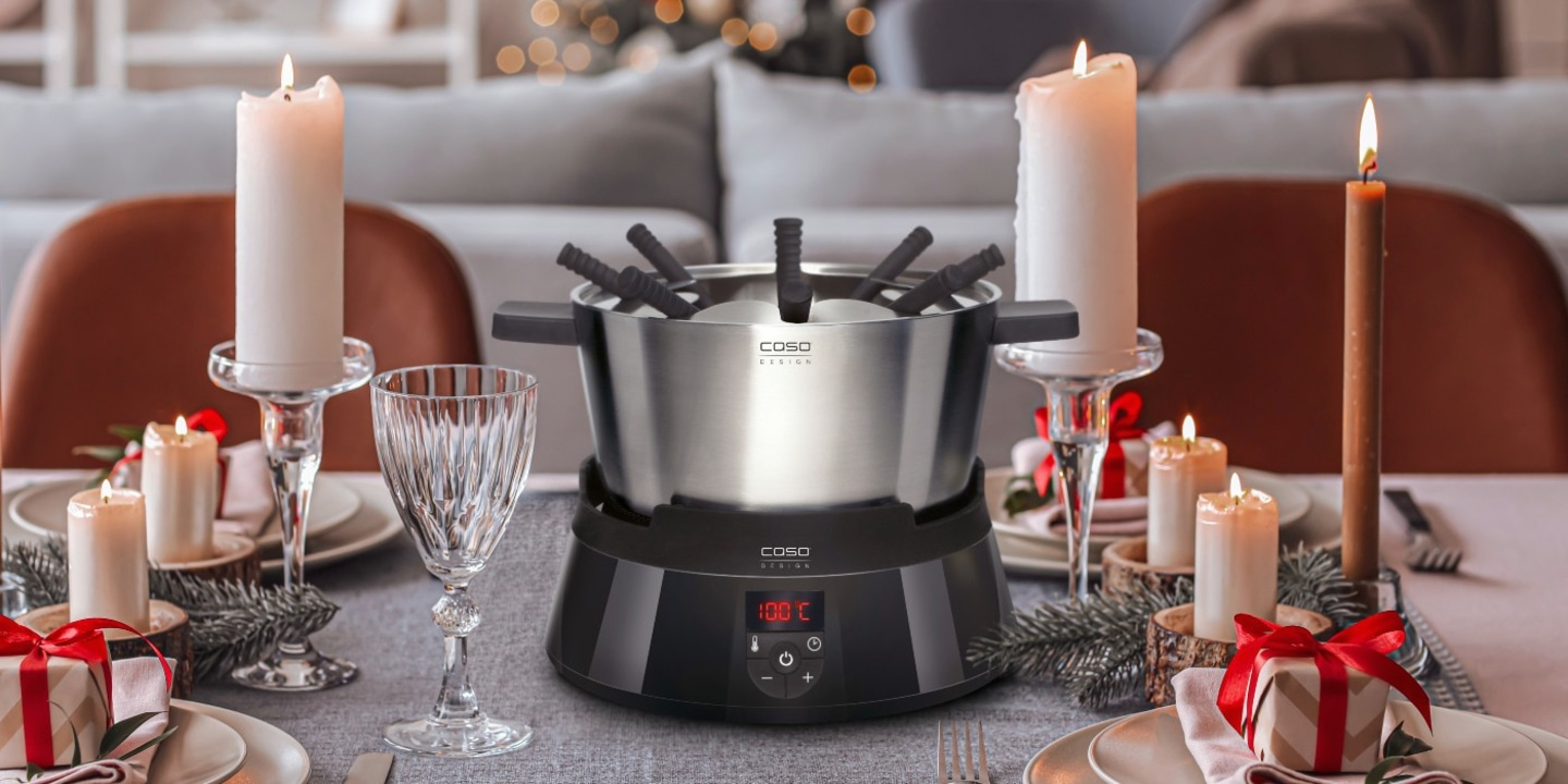 Fondue-Set mit Kerzen und Geschenken auf einem festlich gedeckten Tisch