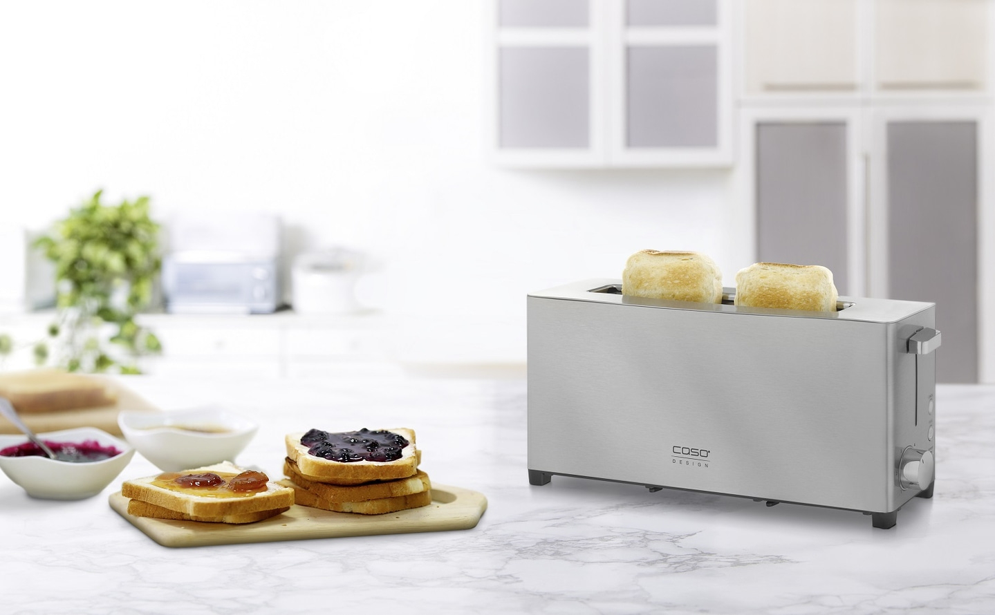 Toaster mit Toastbrotscheiben und Marmelade auf einem Tisch in der Küche.