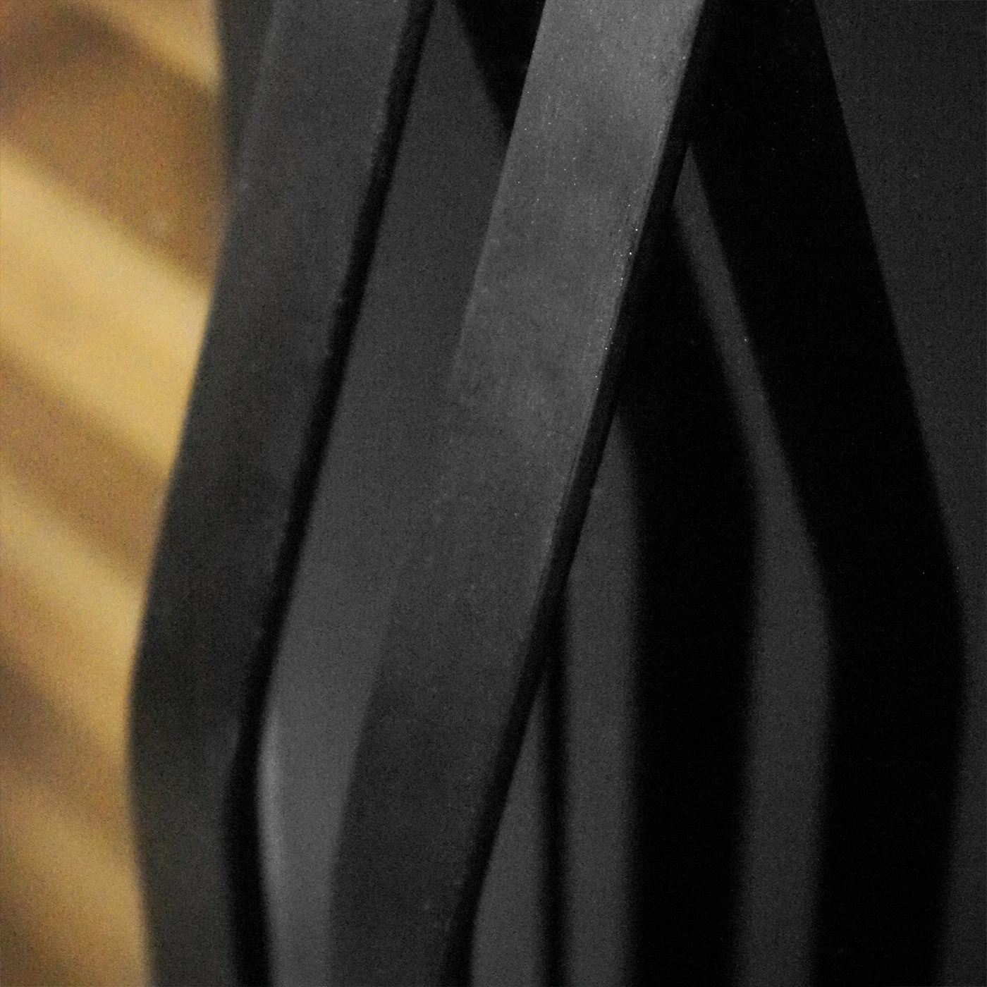 Close-up of black, curved metal strips with wood in the background