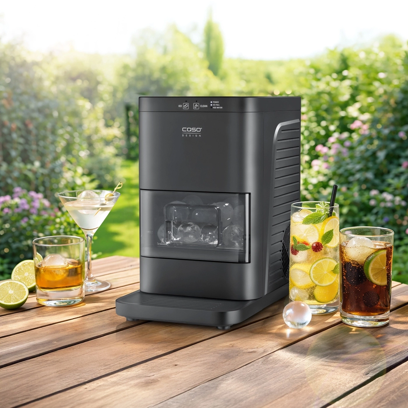 Ice maker with cocktails and ice cubes on a wooden table outdoors