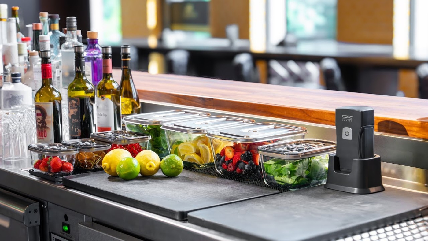 Bar with bottles, containers of fruit, and a vacuum sealing machine.