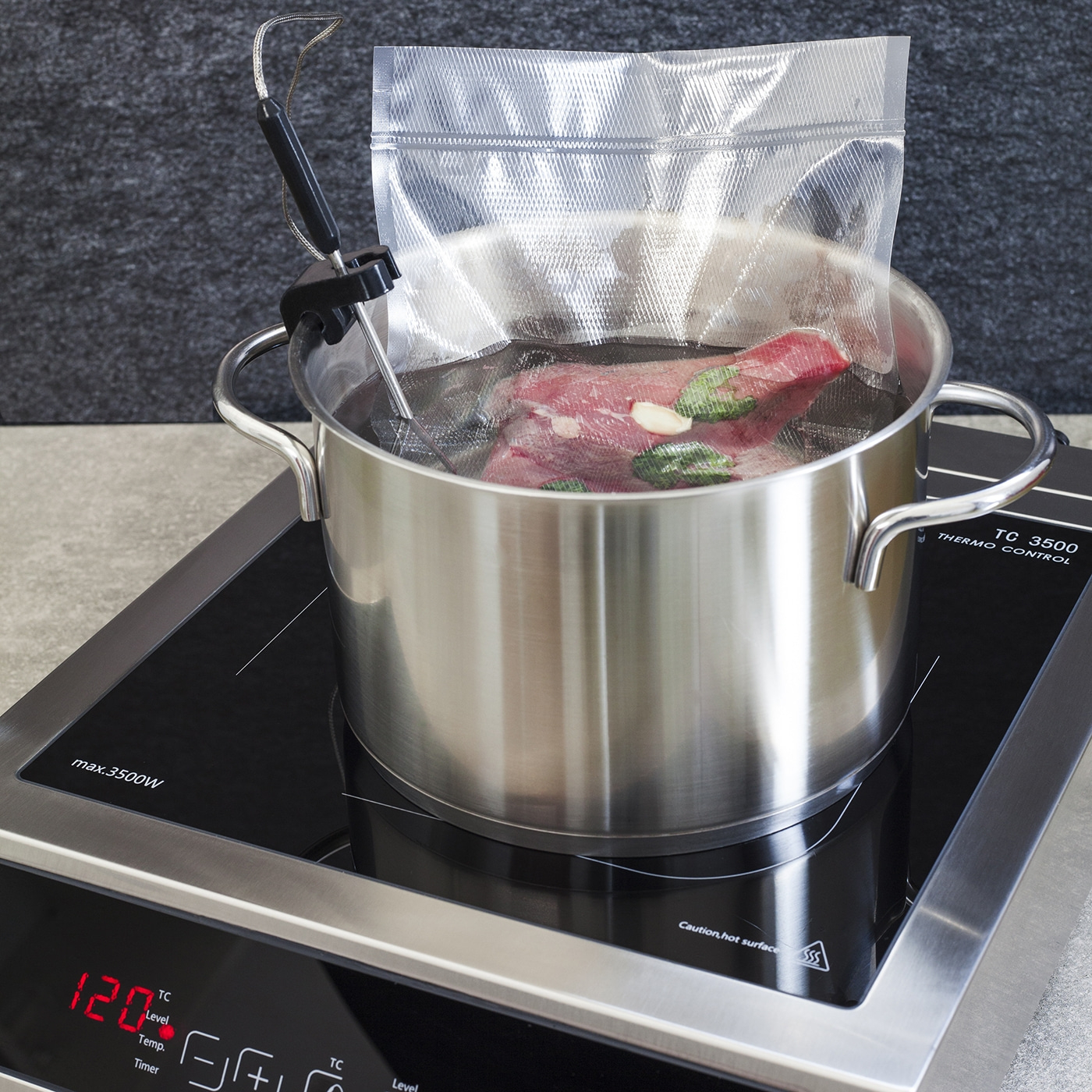 Topf mit Fleisch im Wasserbad auf Induktionskochfeld mit Temperaturanzeige