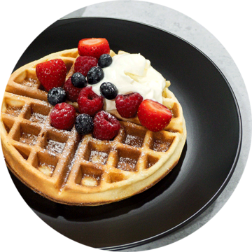 Waffle with berries and cream on a black plate, close-up shot