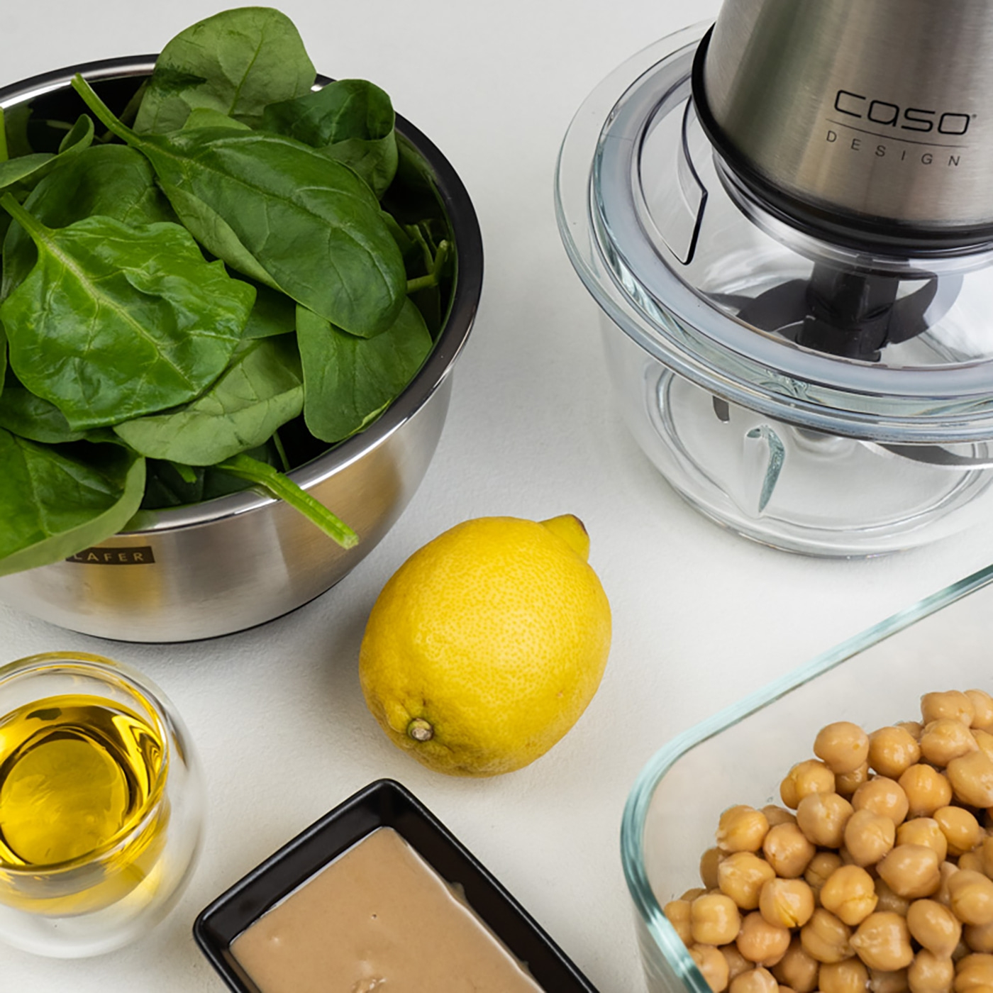 Spinach, lemon, chickpeas, tahini, oil, and blender for hummus preparation