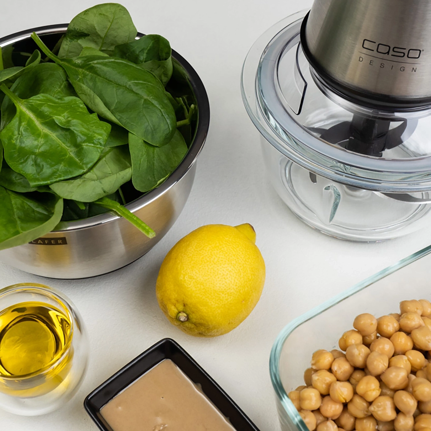 Spinat, Zitrone, Kichererbsen, Tahini, Öl und Mixer für Hummus-Zubereitung