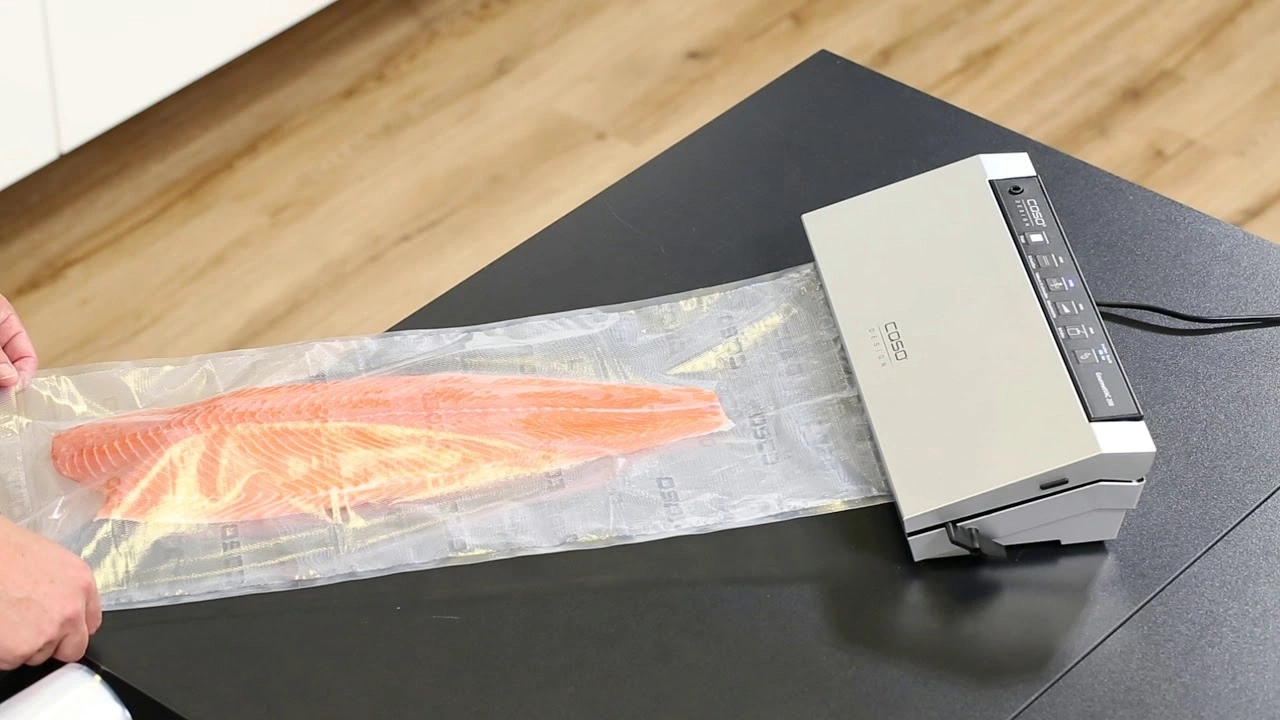 Salmon fillet being vacuum-sealed to preserve freshness with a vacuum sealer machine.