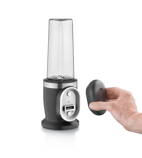 Hand hält magnetischen Akku vor einen Standmixer mit transparentem Behälter und schwarzem Sockel