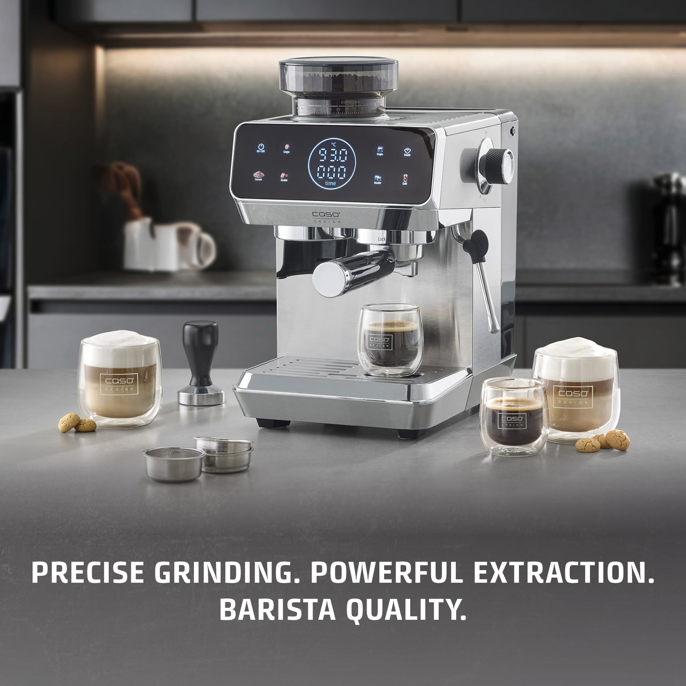 A silver coffee machine with two glasses of coffee and cookies.