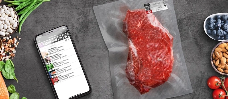 Smartphone with food app, steak, blueberries, almonds and vegetables on gray background.