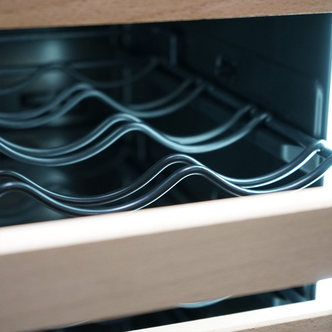 Close-up of a wine fridge with wavy wire racks and wooden frame