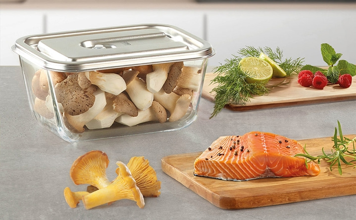 Frischer Lachs, Pilze, Himbeeren, Limette und Kräuter auf Holzbrettern.