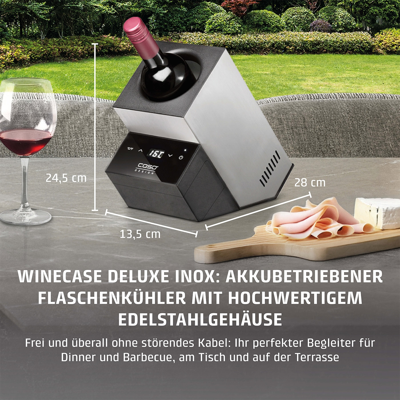 Weinkühler mit Wein, Glas, Käse und Wurst auf dem Tisch im Garten.