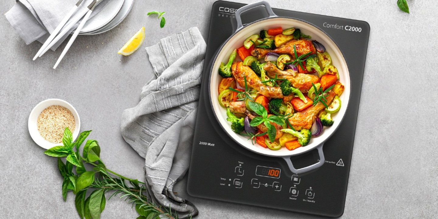 Gebratenes Hähnchen mit Gemüse auf einem Induktionskochfeld