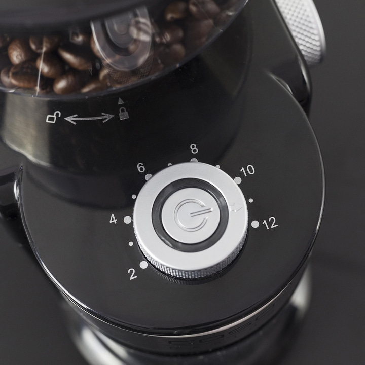 Nahaufnahme eines schwarzen Kaffeemahlers mit Einstellrad und Kaffeebohnen im Behälter.