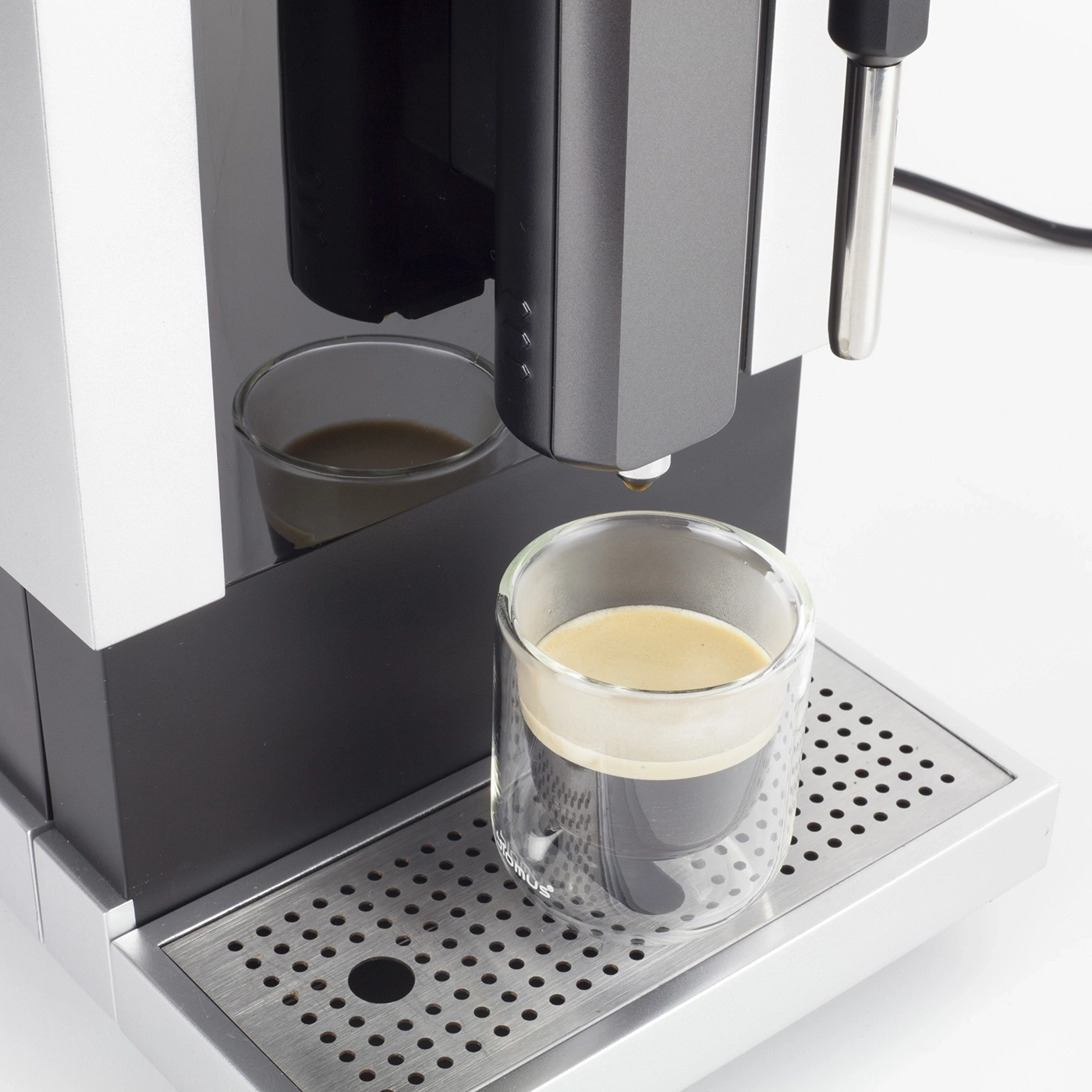 Kaffeemaschine mit Glas, das mit Kaffee gefüllt ist, auf einer silbernen Ablage