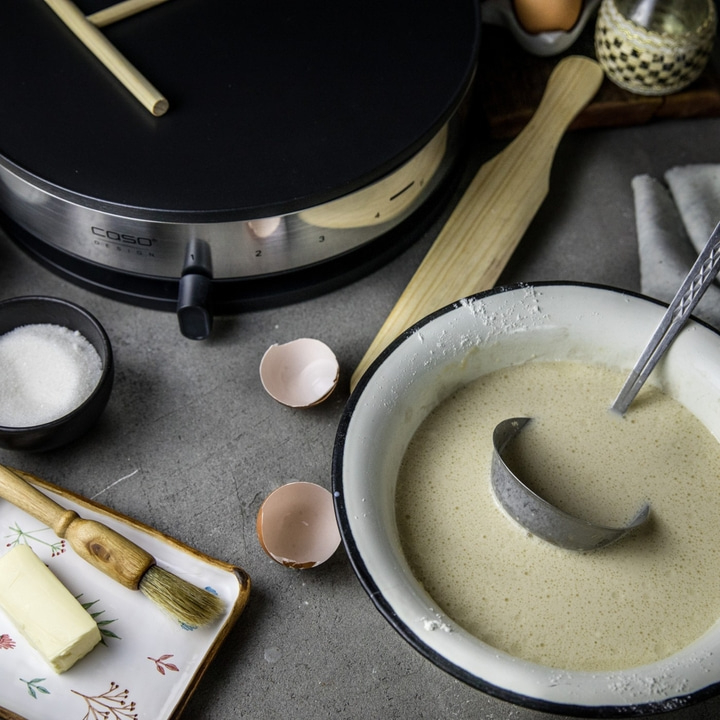 Pancake preparation with ingredients, pancake machine and bowl with batter
