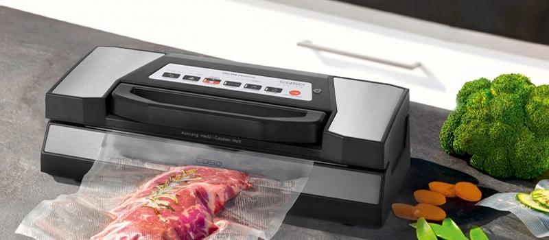 Vacuum sealer with meat and vegetables on a countertop