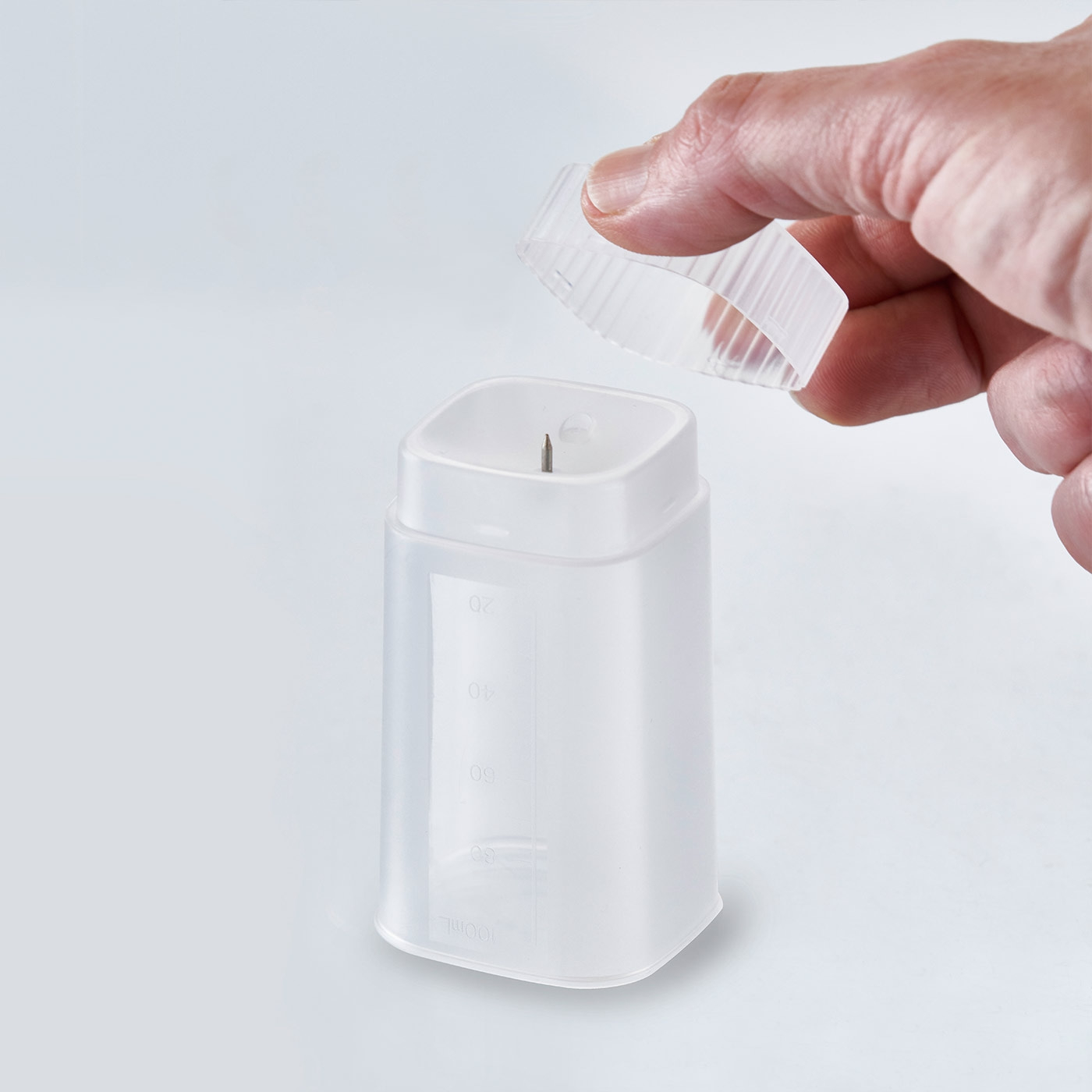 Container with lid and hand. Measuring scale. White background. Close-up shot.
