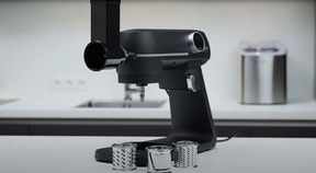 Black kitchen machine with attachments and accessories on white table
