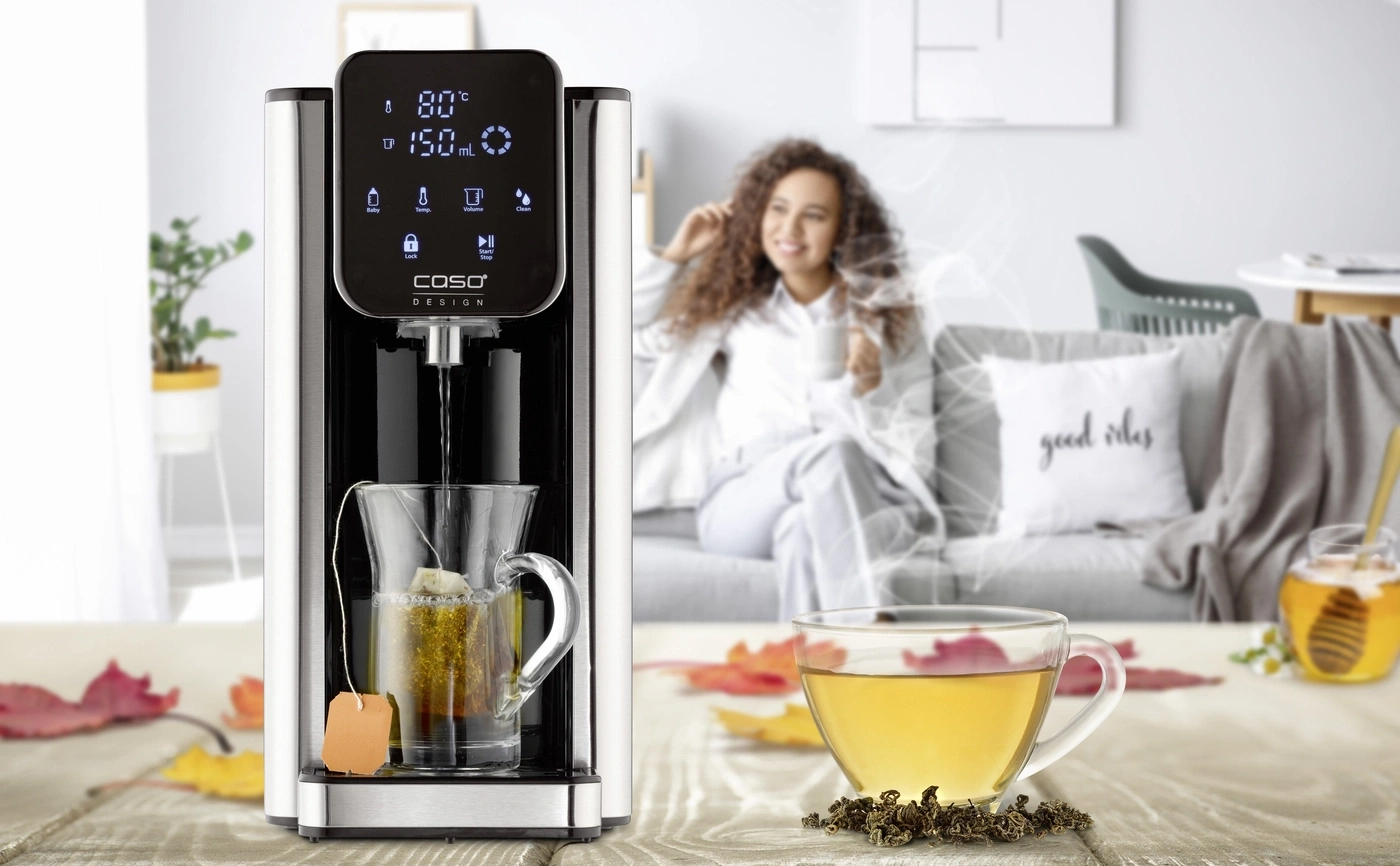 Eine Frau genießt Tee neben einem Wasserkocher mit einer Tasse Tee und Honig.