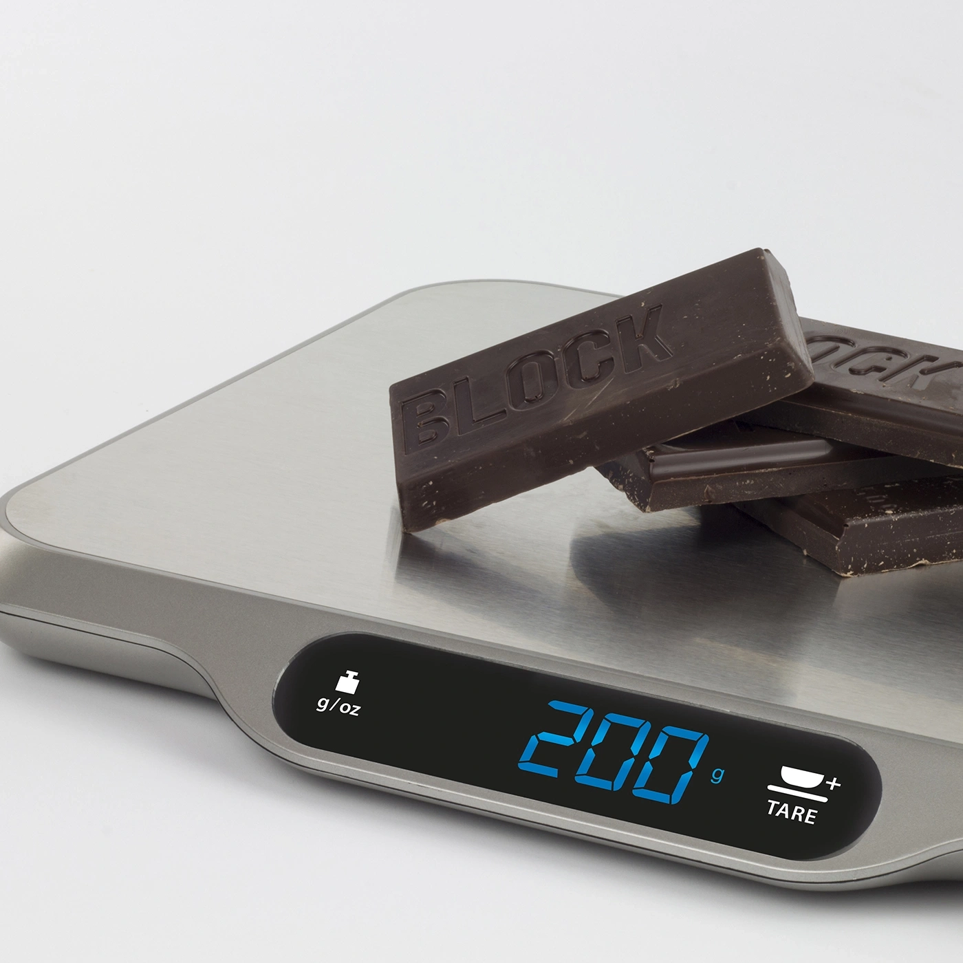 Chocolate pieces on a scale, displaying a weight of 200 grams.