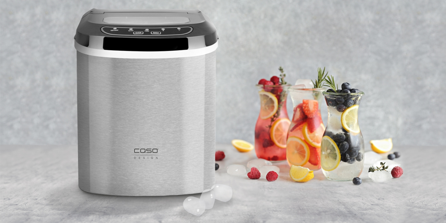 Eiswürfelmaschine mit Getränken und Früchten auf grauem Hintergrund