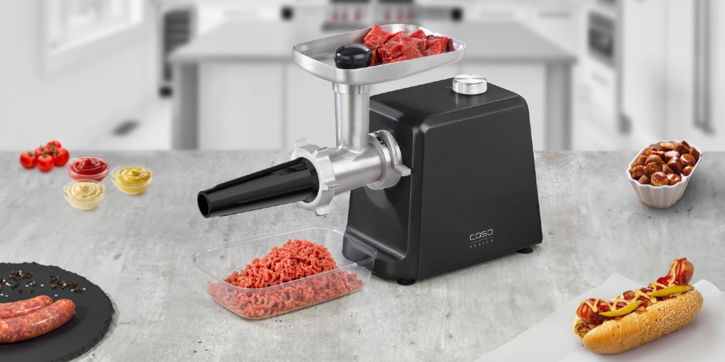 Meat grinder with ingredients and hotdog on a kitchen table