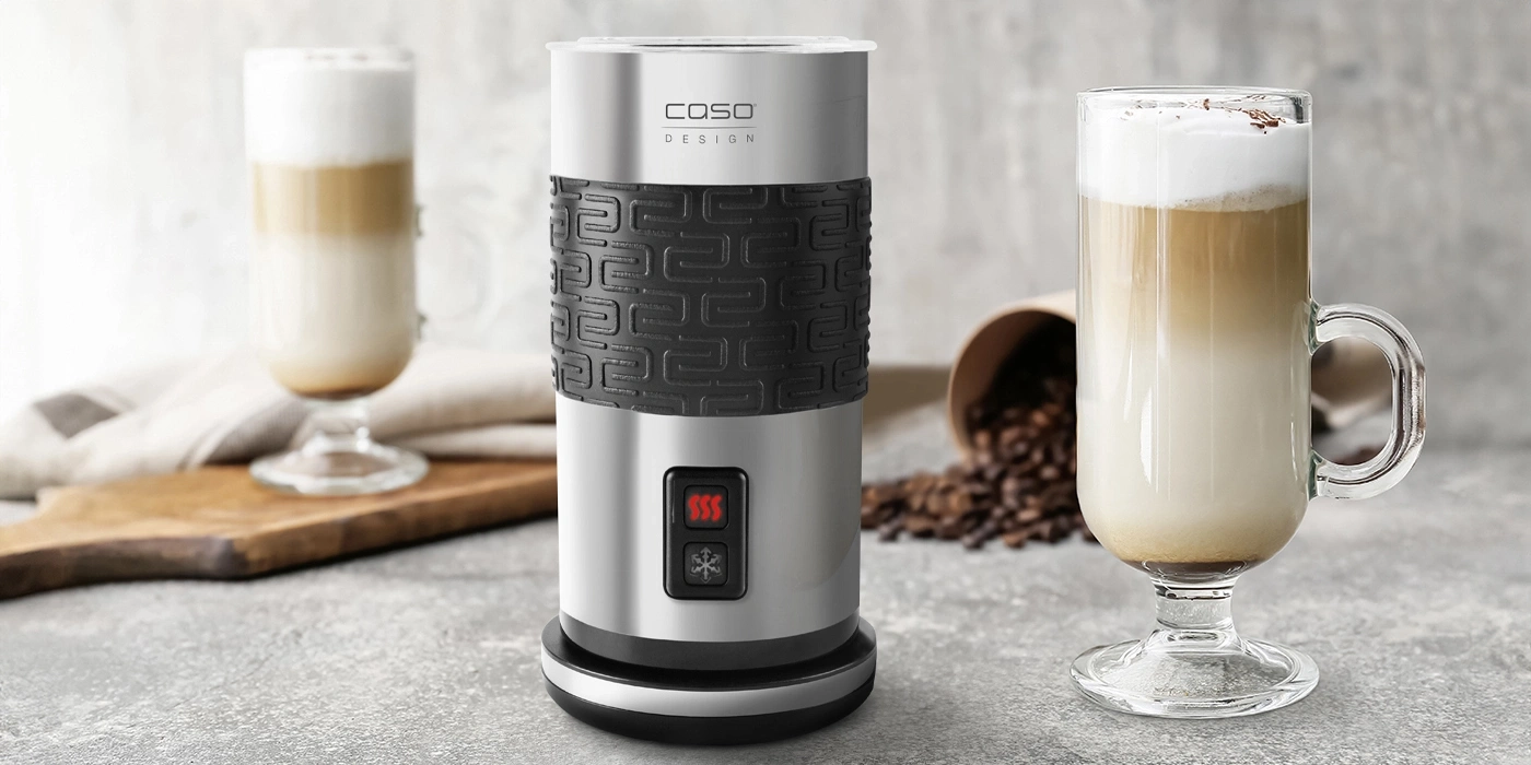 Milchaufschäumer mit Latte Macchiato und Kaffeebohnen auf grauem Hintergrund