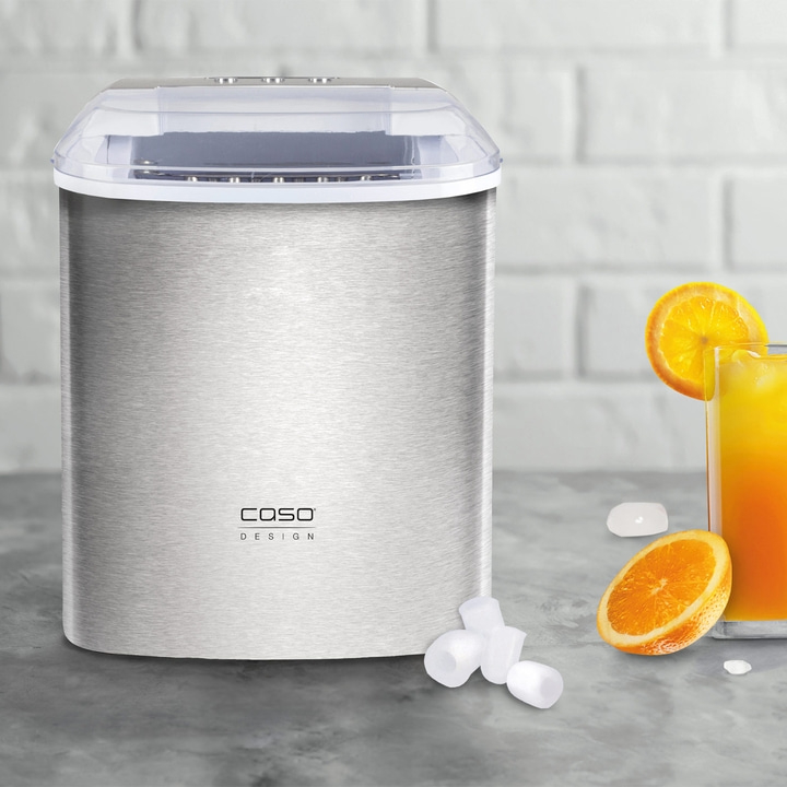 Eiswürfelmaschine mit Orangenscheibe und Getränk auf grauem Untergrund