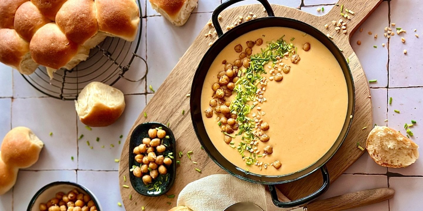 Köstliche Suppe mit Kichererbsen und Brot, serviert auf einem Holzbrett.