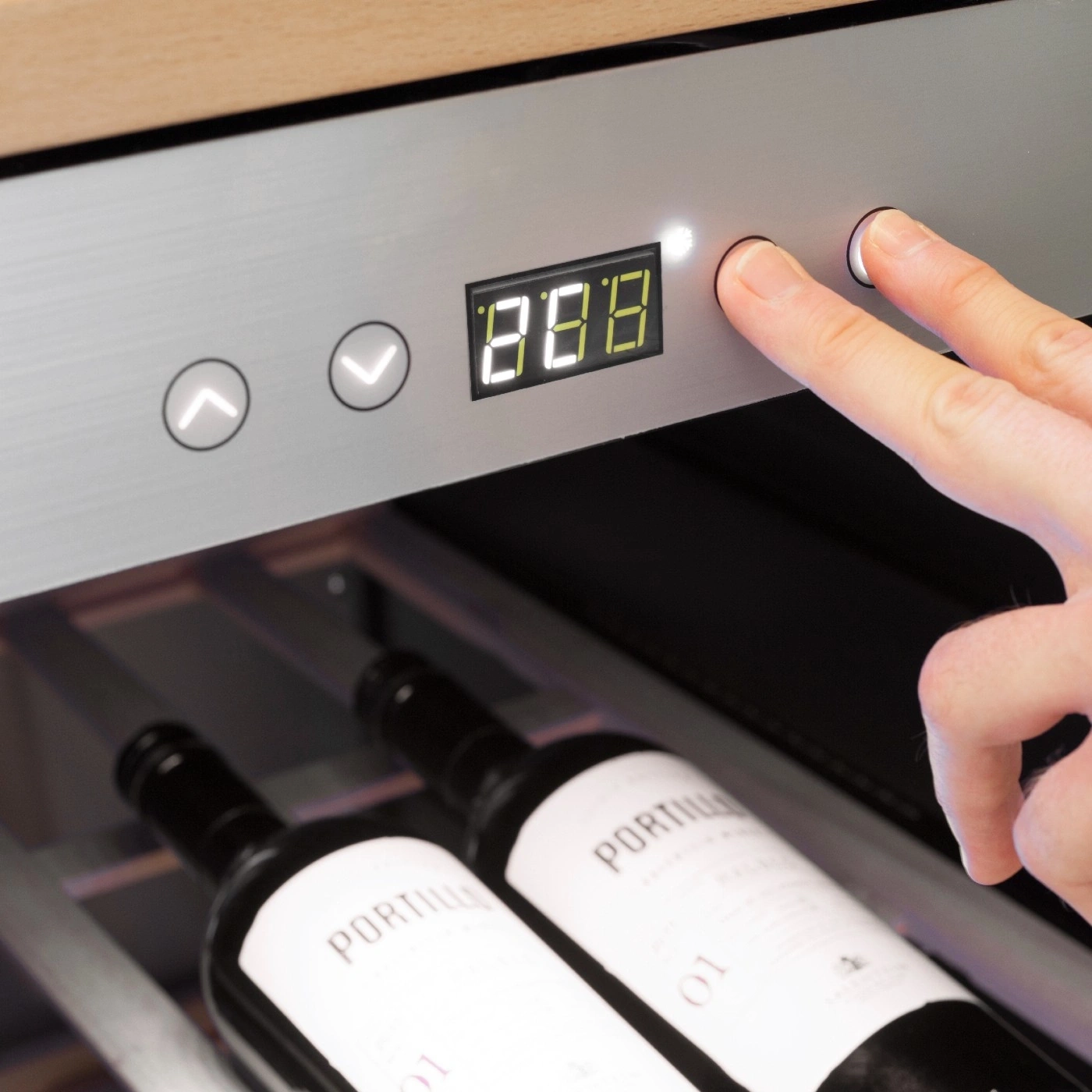 Wine cooler with control panel and wine bottles. Person pressing buttons.