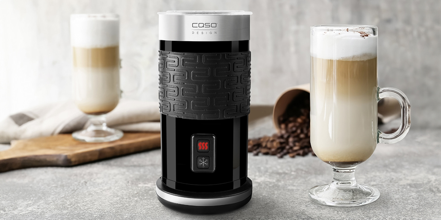 Milchaufschäumer mit Latte Macchiato und Kaffeebohnen auf grauem Hintergrund