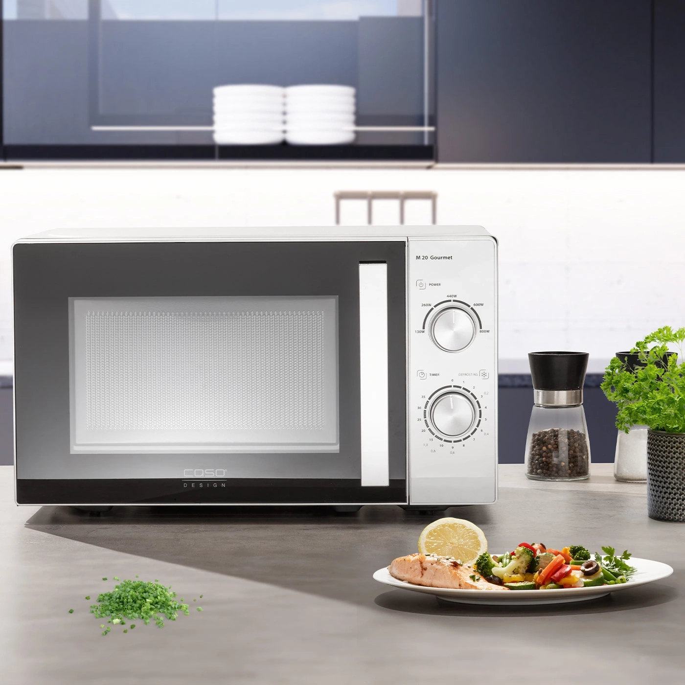 Microwave with food on a table in a kitchen. Caso Design M 20 Gourmet.