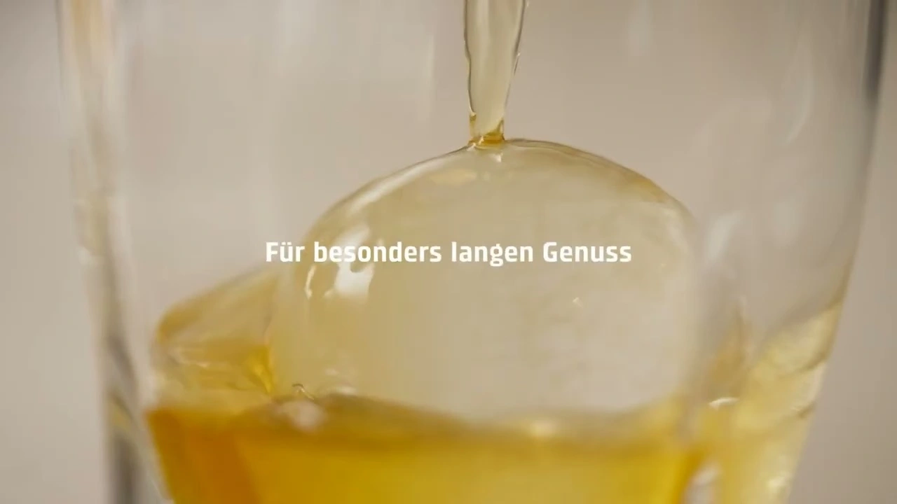 Liquid flows onto an ice ball in a glass for long enjoyment.