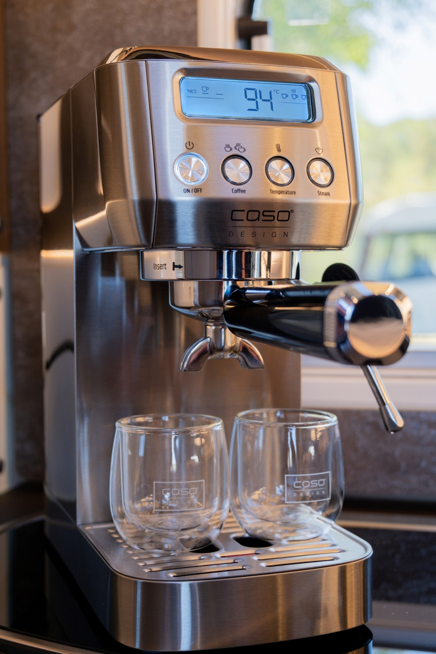 Eine silberne Espressomaschine mit zwei Gläsern und einem digitalen Display.