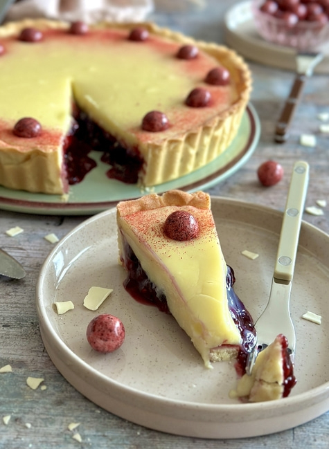 Delicious tart with berries and cream, served on a plate with a fork.