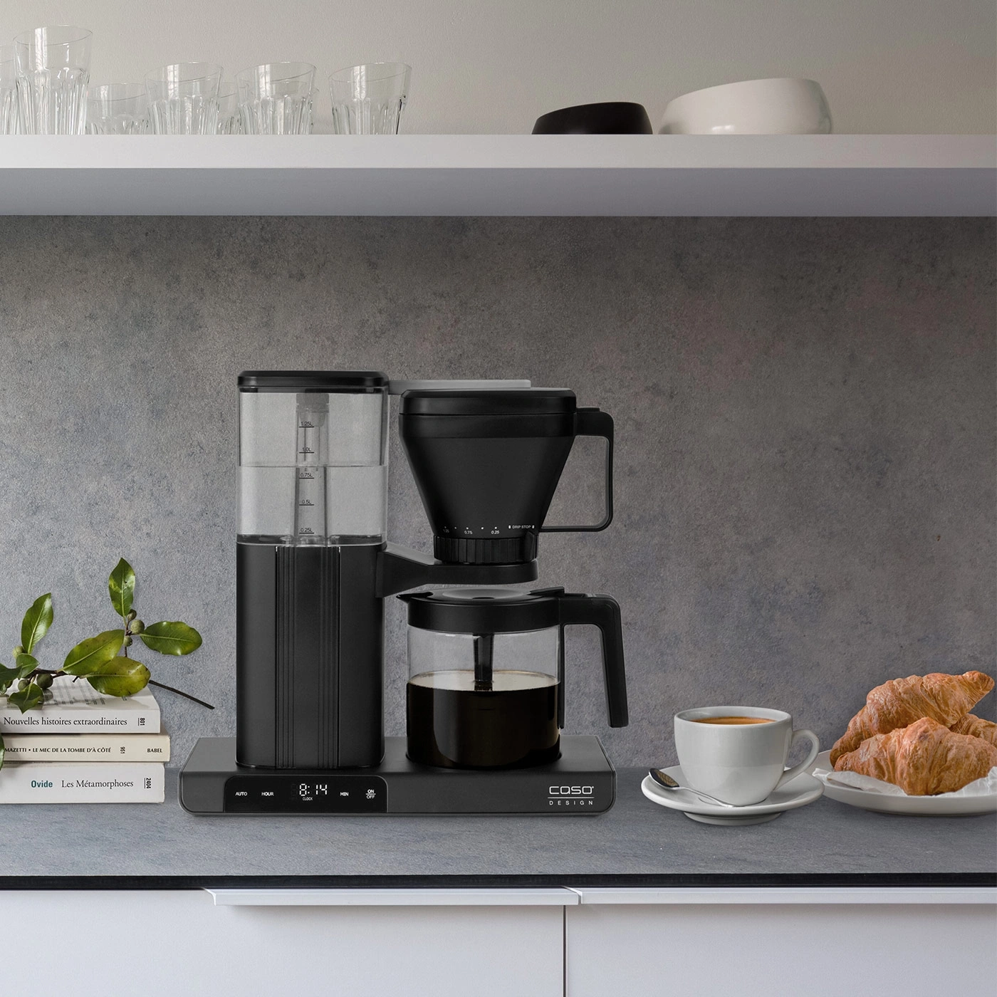 Coffee machine with coffee, croissants, and cup on a kitchen countertop.