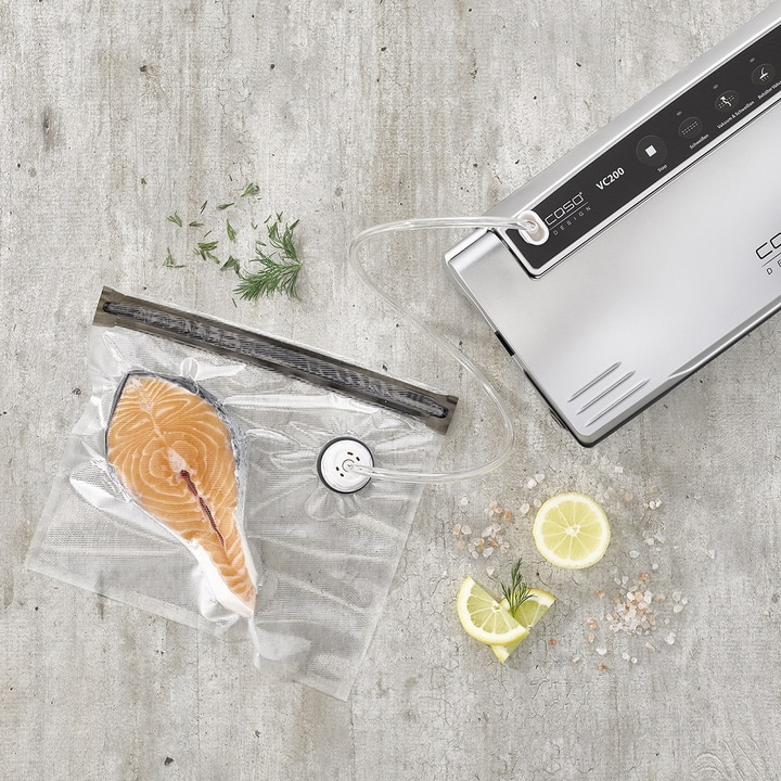 Salmon fillet being vacuum packed with lemon and herbs, food preparation.