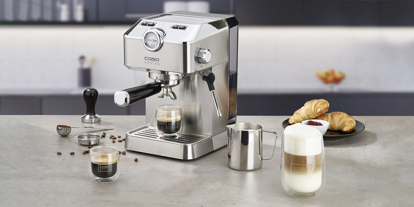 Kaffeemaschine mit Kaffee, Croissants und Milchgetränk auf einem Tisch.