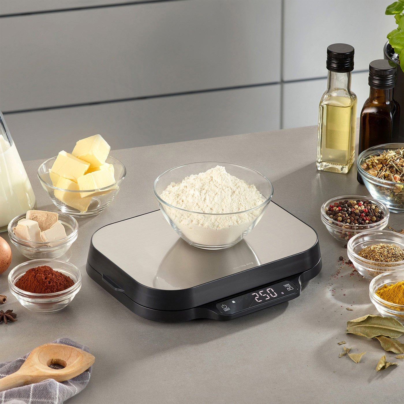Küchenwaage mit Zutaten für Backwaren, Mehl, Butter, Gewürze, Öl, Eier.
