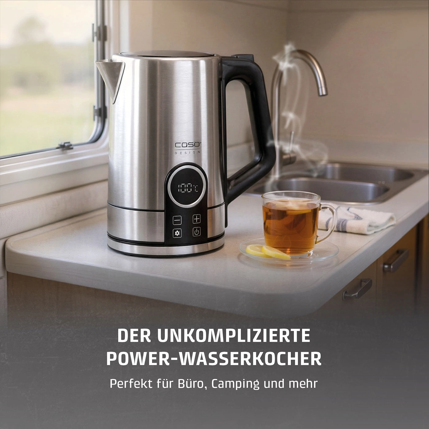 Ein Wasserkocher aus Edelstahl mit einer Temperaturanzeige auf 100 Grad Celsius daneben eine Tasse Tee.