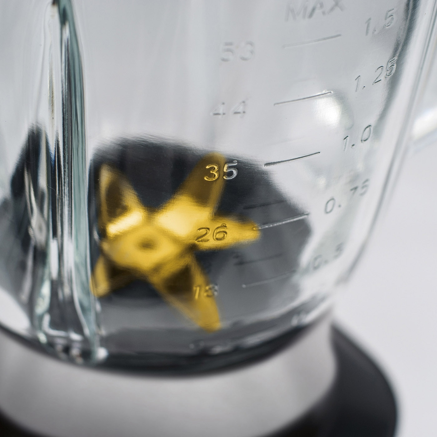 Close-up of a blender with measurement scale and golden blades inside